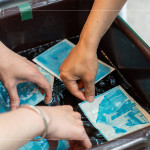 將明信片輕放入水箱中，清洗掉藥水後，隨著雙氧水的洗禮，藍(lán)曬圖像逐漸浮現(xiàn)。